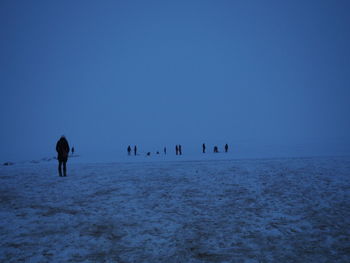 Silhouette people walking on landscape against clear blue sky