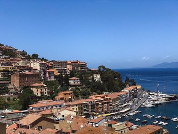 High angle view of townscape by sea against blue sky