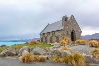 Old building by rocks against sky