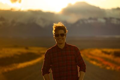 Portrait of young man standing against mountain during sunset