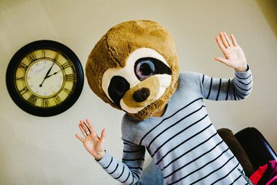 Full length of woman wearing mask gesturing against wall