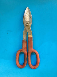 Directly above view of old orange scissors on blue table