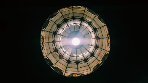 Low angle view of illuminated lighting equipment against black background