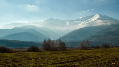 Scenic view of field and mountains against sky