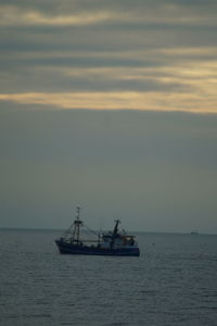 Boat sailing in sea at sunset