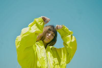 Portrait of young woman holding seashell against blue background