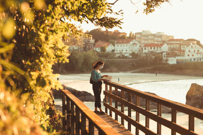 Woman standing by railing against trees