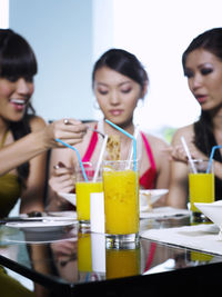 Female friends eating spaghetti while sitting in restaurant