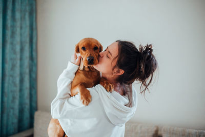 Side view of woman holding dog at home