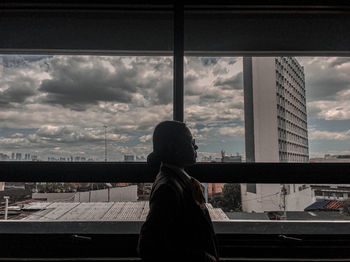 Woman looking at cityscape seen through window