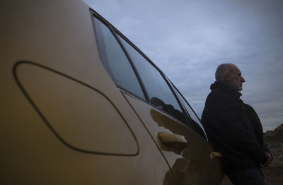 Adult man standing against car looking at view during sunset. almeria, spain