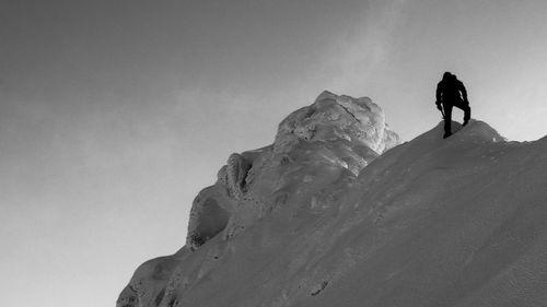 Low angle view of silhouette man against mountain during winter