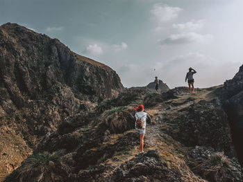 People on rock against sky