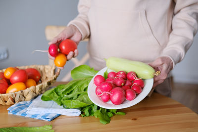 Midsection of woman holding tomatoes on table