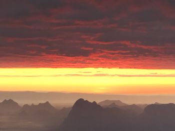 Scenic view of dramatic sky over silhouette mountains during sunset
