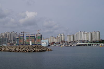 Sea by cityscape against sky