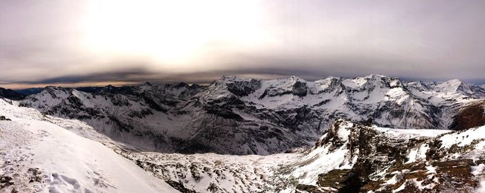 Panoramic view of snow covered mountains against sky