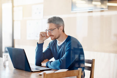 Young man using mobile phone while sitting on table