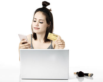Young woman using smart phone against white background