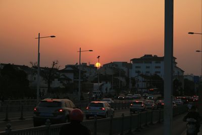 Cars on city street against orange sky