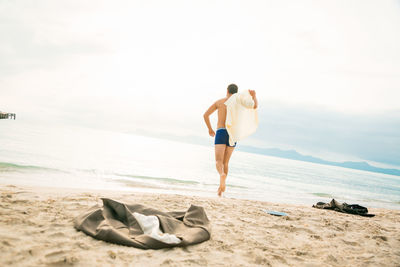 Rear view of men on beach against sky