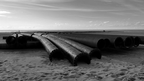 Deck chairs on beach against sky