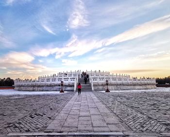 People on beach against cloudy sky