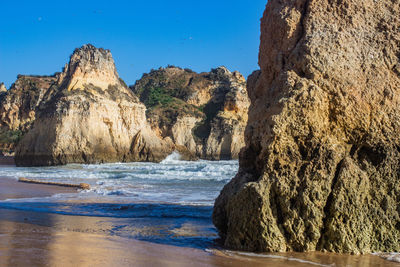 Rock formation on beach against clear sky