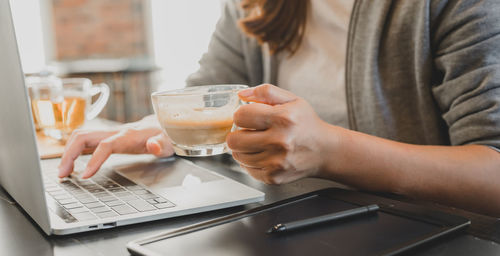Midsection of woman using laptop on table