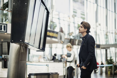 Businessman reading arrival departure board at airport