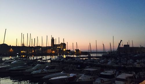 Sailboats moored in sea against clear sky during sunset