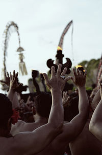 Rear view of men dancing in music concert against sky