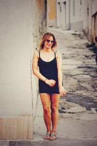 Portrait of young woman standing against wall