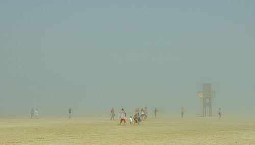 Fog over the beach, people walking on the beach