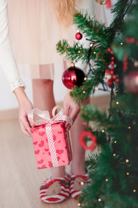 Midsection of woman with christmas tree at home