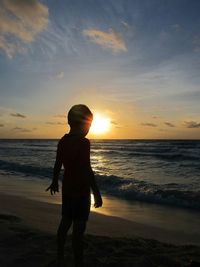 Silhouette of people on beach at sunset