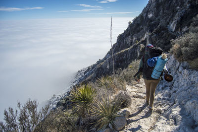 Woman standing on rock against cloudscape