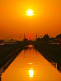 Bridge over river against orange sky during sunset