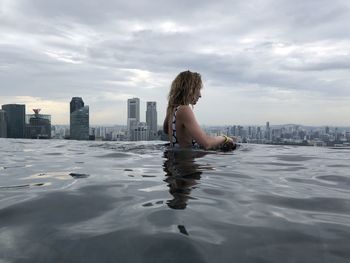 Woman in swimming pool against buildings in city