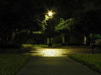 Illuminated street light on walkway at night