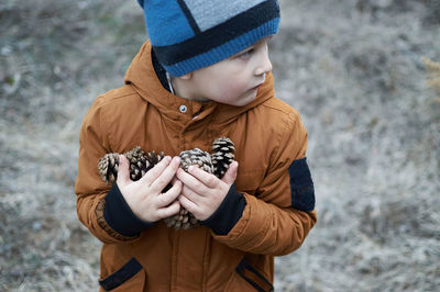 Midsection of boy holding hat while standing outdoors