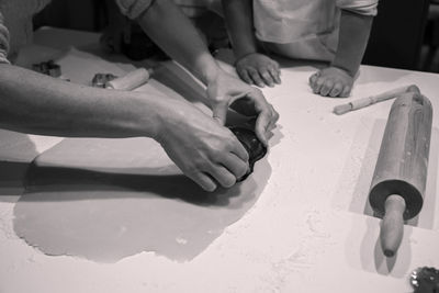 Cropped hands of woman making cookies on table in kitchen