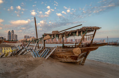 Fishing boats moored on beach against sky