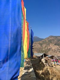 Flags on retaining wall against clear blue sky