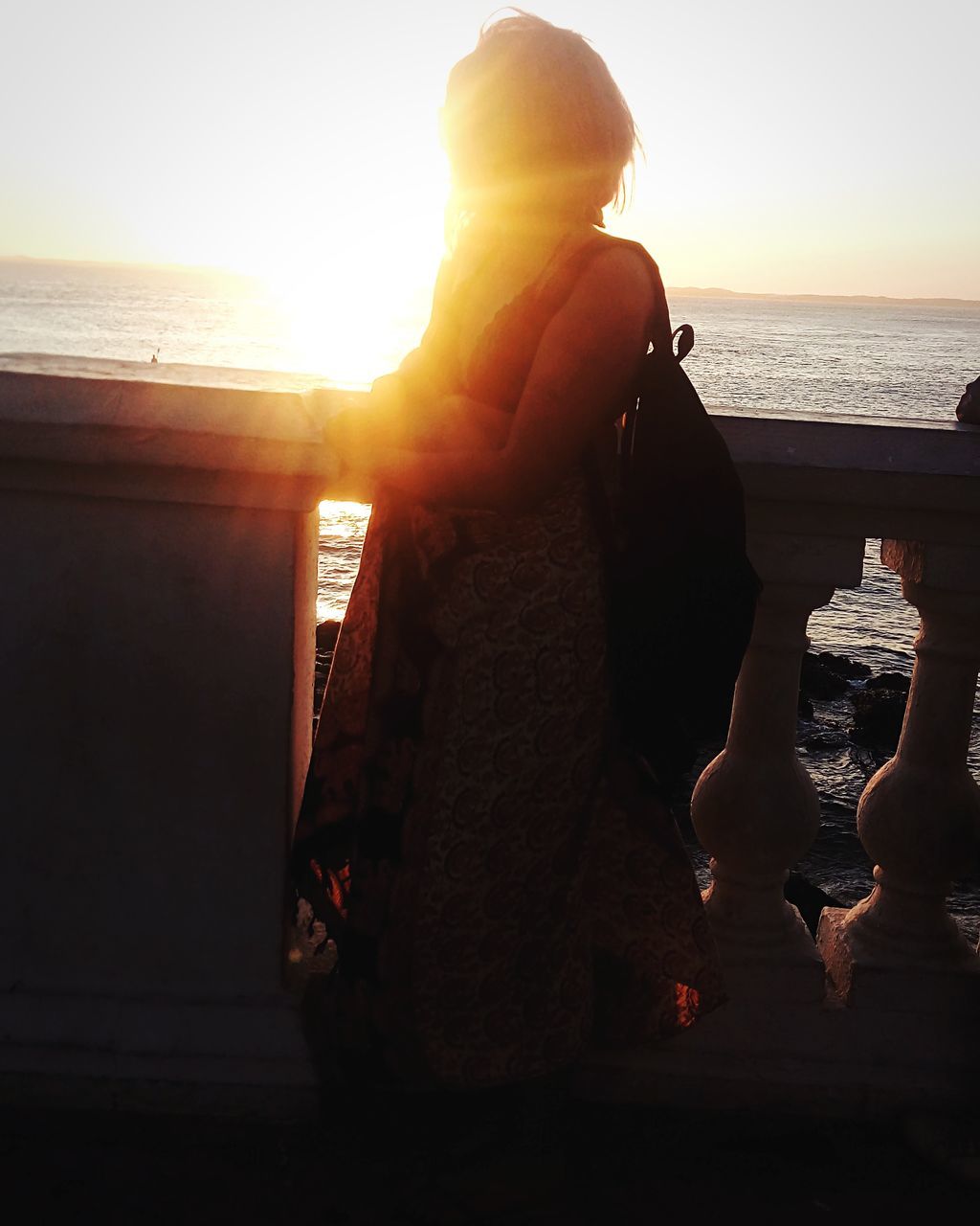 WOMAN STANDING ON BEACH DURING SUNSET