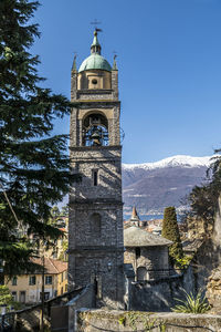 The bellano stone bell tower with the snow-capped alps in the background