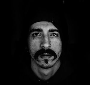 Portrait of young man against black background