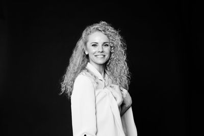 Portrait of a smiling young woman against black background