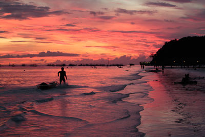 Silhouette people on beach against sky during sunset