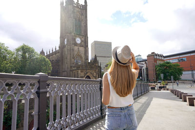 Back view of beautiful woman visiting the city of manchester on sunny day in england, united kingdom